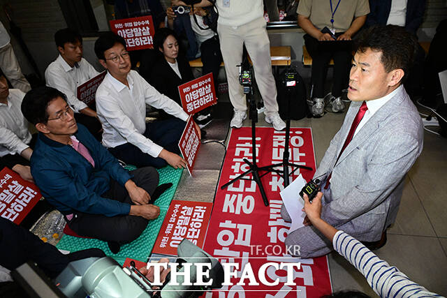 중앙윤리위원회의에 출석해 자신의 징계 여부에 대한 소명을 마친 전한길 씨가 국민의힘 당사 특검 압수수색 저지를 위해 농성 중인 김문수 당대표 후보(왼쪽) 앞에 무릎을 꿇고 징계에 대한 입장을 밝히고 있다.