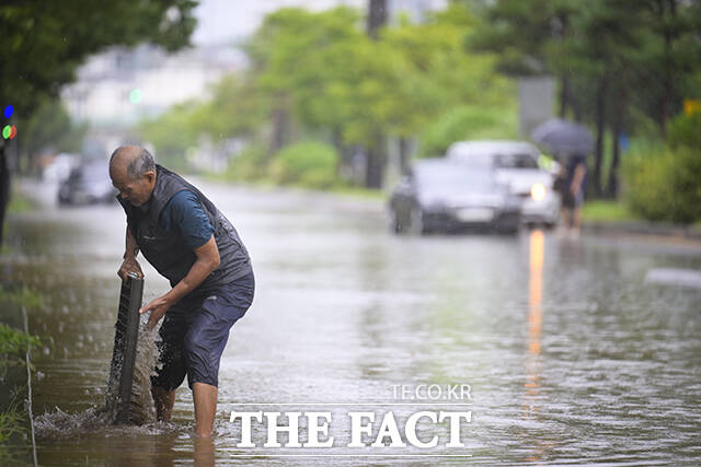 14일 기상청에 따르면 서해상에서 강하게 발달한 비구름대가 지속 유입됨에 따라 이날 아침 수도권을 중심으로 시간당 30~70㎜, 오전까지 수도권과 강원 내륙, 강원 북부 산지와 충남 북부를 중심으로 시간당 30㎜ 안팎의 매우 강하고 많은 비가 내리고 있다. 사진은 전날 오후 경기 고양시 덕양구 행주IC 접근로가 침수돼 한 시민이 배수로를 청소하고 있는 모습. /고양=장윤석 기자