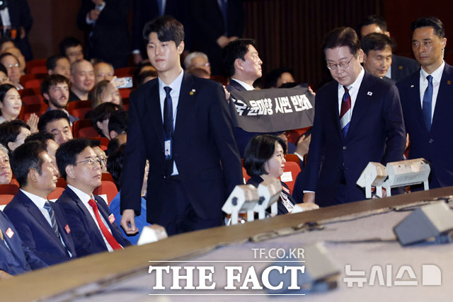 국민의힘 8.22 전당대회에 출마한 안철수 후보가 광복절 경축식 도중 이재명 대통령을 향해 공개 항의에 나섰다. ‘조국·윤미향 사면 반대’라는 문구가 적힌 플래카드를 들고 대통령 경축사 도중 일어선 것이다. /뉴시