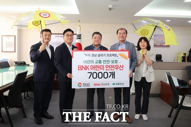 허종구 경남은행 부행장(왼쪽 두 번째)이 박명균 경남도 행정부지사(가운데)에게 어린이 안전우산 기탁증서를 전달한 뒤 기념촬영을 하고 있다./경남도