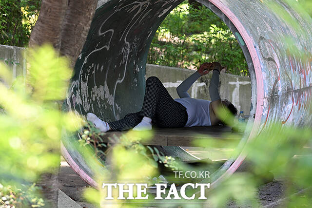 한 시민이 그늘에 누워서 휴식을 취하고 있다.