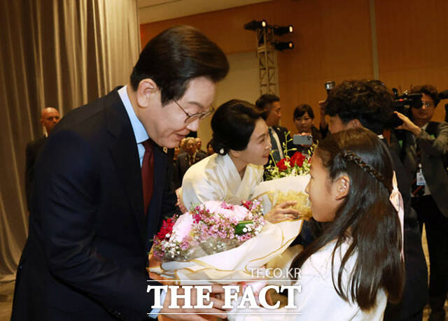 이재명 대통령과 김혜경 여사가 화동에게 꽃다발을 받고 있다.