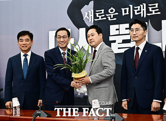 우상호 대통령실 정무수석이 27일 오후 서울 여의도 국회에서 장동혁 국민의힘 신임 당 대표를 예방하며 이재명 대통령이 보낸 축하난을 선물하고 있다. /국회=배정한 기자