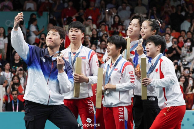 북한 탁구도 복식이 강하다 화제의 사진. 2024 파리 올림픽 혼합복식 시상식에서 금, 은, 동 메달을 딴 중국-북한-한국 선수들이 한국산 휴대폰으로 셀카를 찍는 모습. 북한은 2022 항저우 아시안게임 여자복식에서도 한국의 신유빈-전지희 조에 이어 은메달을 딴 바 있다. / 뉴시스