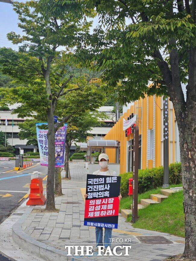 의왕시정감시연대 활동가가 22일 의왕시청 앞에서 건진법사 전성배 씨와 김성제 의왕시장의 무민공원 연루 의혹을 제기하며 피켓 시위를 벌이고 있다./의왕시정감시연대