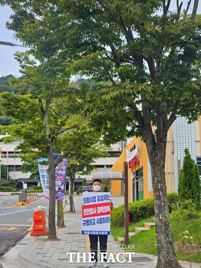 의왕시정감시연대 활동가가 22일 의왕시청 앞에서 건진법사 전성배 씨와 김성제 의왕시장의 무민공원 연루 의혹을 제기하며 피켓 시위를 벌이고 있다./의왕시정감시연대