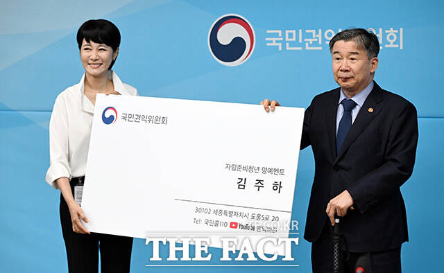 김주하 MBN 특임상무(왼쪽)가 24일 오전 서울 종로구 정부서울청사에서 열린 국민권익위원회 자립준비청년 멘토 위촉식에 참석해 유철환 위원장으로부터 받은 대형 명함을 들고 포즈를 취하고 있다. /임영무 기자