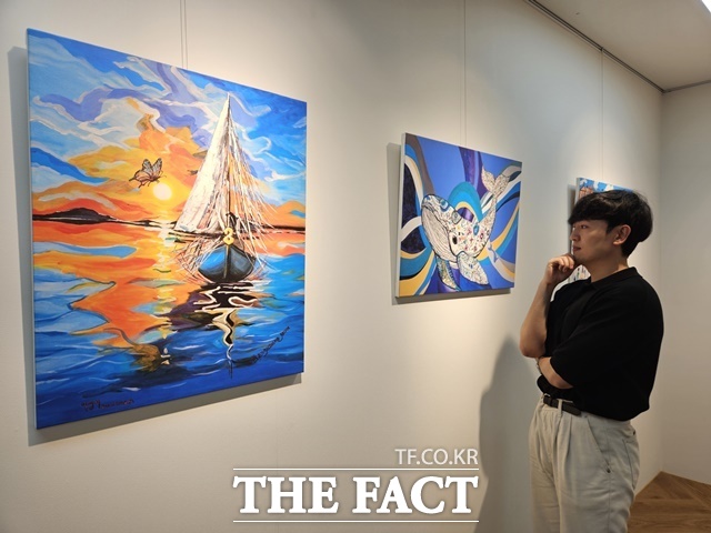 현대제철 직원이 ㈜올모용인 사업장에 걸린 소속 발달장애인 작가들의 작품을 감상하고 있다. /현대제철