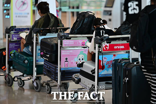 출국 수속을 앞둔 여객이 카트에 앉아 독서를 하는 모습.