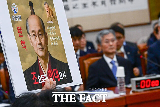 최혁진 무소속 의원이 13일 오전 서울 여의도 국회 법제사법위원회에서 열린 대법원 등에 대한 국정감사에서 조희대 대법원장(오른쪽)을 향해 항의 피켓을 들고 있다. /국회=남윤호 기자