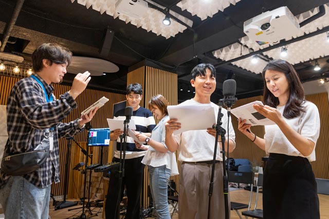 코웨이 임직원이 동화 낭독을 위해 전문 성우의 발성 교육과 목소리 훈련을 받고 스튜디오에서 녹음을 하고 있다. /코웨이