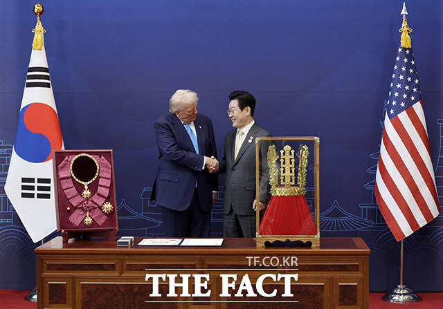 이재명 대통령이 29일 경북 경주박물관에서 도널드 트럼프 미국 대통령에게 천마총 금관 모형을 선물한 뒤 악수하고 있다. 왼쪽은 이 대통령이 트럼프 대통령에게 수여한 무궁화 대훈장. /APEC 2025 KOREA & 연합뉴스