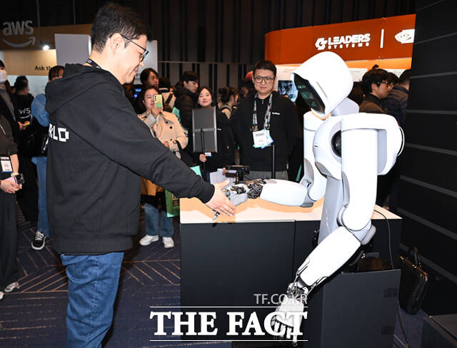 3일 서울 강남구 코엑스에서 SK AI 서밋 2025(SK AI Summit 2025)이 열린 가운데, 인공지능 스타트업 리얼월드(RLWORLD) 관계자와 휴머노이드 로봇 알렉스(ALLEX)가 악수하고 있다. /이새롬 기자