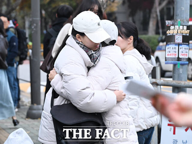 한 수험생이 교문 앞에서 어머니와 포옹하고 있다.