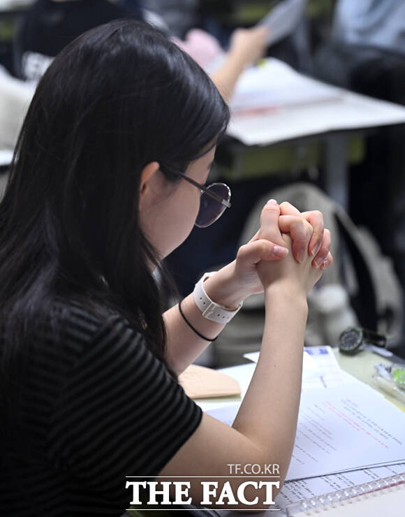 한 수험생이 시험 시작을 기다리며 양 손을 모아 기도하고 있다.