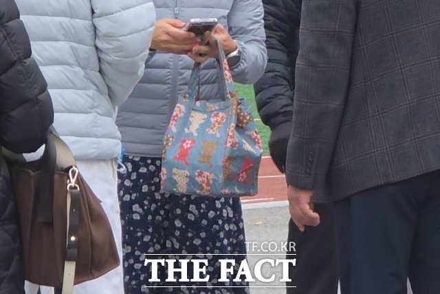 13일 오전 서울 광진구 광남고등학교에서 감독관이 응시장에 들고 가지 못한 수험생의 도시락을 대신 전달해주고 있다. /서울 광남고=유영림 기자