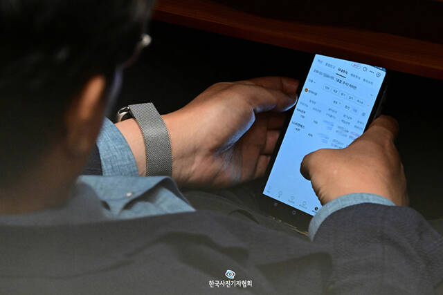 <이달의보도사진상 - 최우수상> 국회 법제사법위원장을 맡고 있는 이춘석 더불어민주당 의원(전북 익산시갑)이 8월 4일 서울 여의도 국회에서 열린 본회의에 참석해 타인의 명의로 주식 거래를 하고 있다. 이 의원의 휴대전화 속 주식 계좌의 주인 차모 씨는 이 의원을 국회 사무총장때부터 보좌해온 인물이다. 이재명 정부가 '코스피 5000' 시대를 추진하는 시점에서 국회 법제사법위원장을 맡고 있는 여당 4선 중진 의원의 '차명 주식 거래'는 적잖은 파장을 일으킬 것으로 예상된다. <금융실명거래 및 비밀보장에 관한 법률>은 모든 금융거래를 실명으로만 할 수 있도록 규정한 법률로 금융거래의 투명성을 확보하고 자금세탁 및 탈세와 같은 경제범죄를 예방하기 위해 엄격하게 시행되고 있다. 불법 목적으로 차명 거래를 한 경우, 5년 이하의 징역 또는 5000만원 이하의 벌금에 처해진다. 자신의 계좌정보를 제공하거나 차명계좌를 개설해준 것처럼 타인의 금융실명법 위반을 도운 경우에도 방조행위가 되어 동일한 처벌을 받을 수 있다. <남윤호기자/ 더팩트/ 한국사진기자협회 - 무단전재 재배포금지>