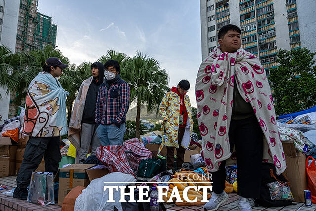 화재 현장 인근 상가 주변에서 주민들이 기부된 물품 속에 서 있다. /홍콩=AP.뉴시스