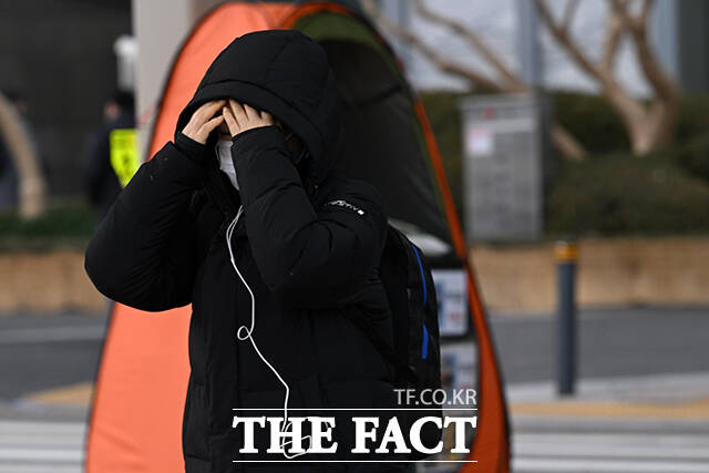 한 시민이 추위로 붉어진 손을 따뜻한 음료로 녹이고 있다.