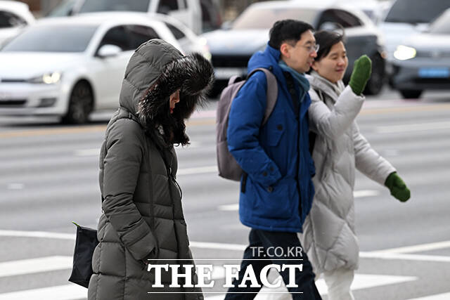 한 시민이 추위로 붉어진 손을 따뜻한 음료로 녹이고 있다.