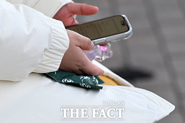 한 시민이 추위로 붉어진 손을 따뜻한 음료로 녹이고 있다.