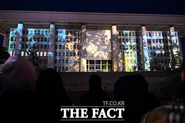 국회의사당에 12·3 비상계엄 사태 당시 계엄군과 국회의 충돌을 담은 영상이 반영되고 있다.