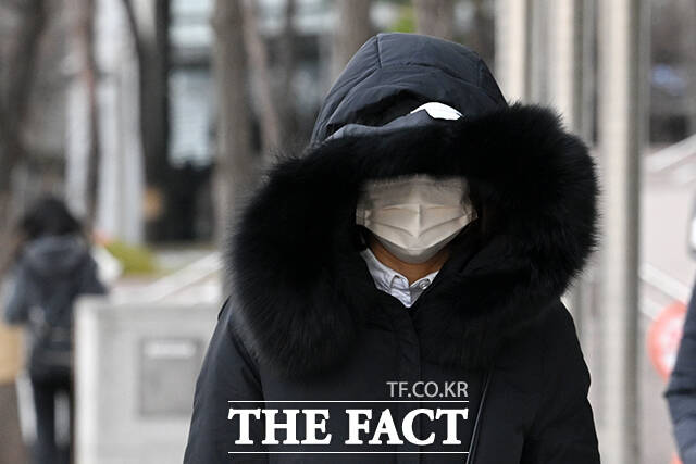 한 시민이 추위로 붉어진 손을 따뜻한 음료로 녹이고 있다.