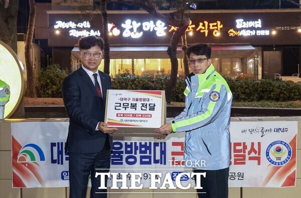 최충규 대전 대덕구청장(왼쪽)이 3일 송촌어린이공원에서 자율방범대에 근무복을 전달하고 있다. /대덕구