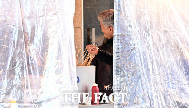 '추위에는 역시 뜨끈한 어묵' 한 남성이 분식 판매대에서 어묵을 먹고 있다.