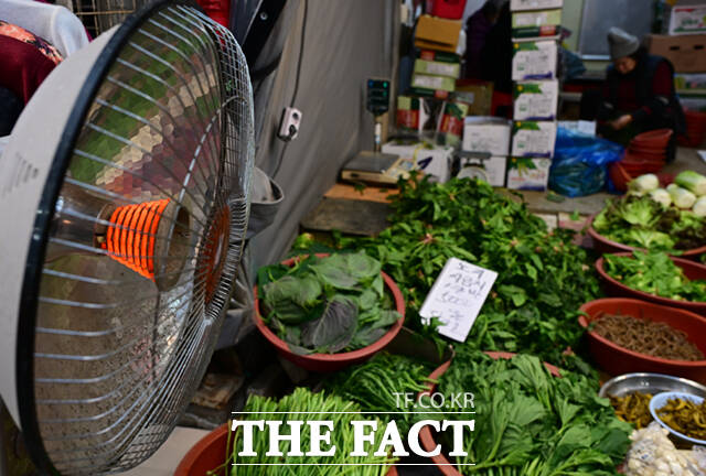 한 채소가게에 진열된 채소들 옆으로 난로가 놓여 있다.