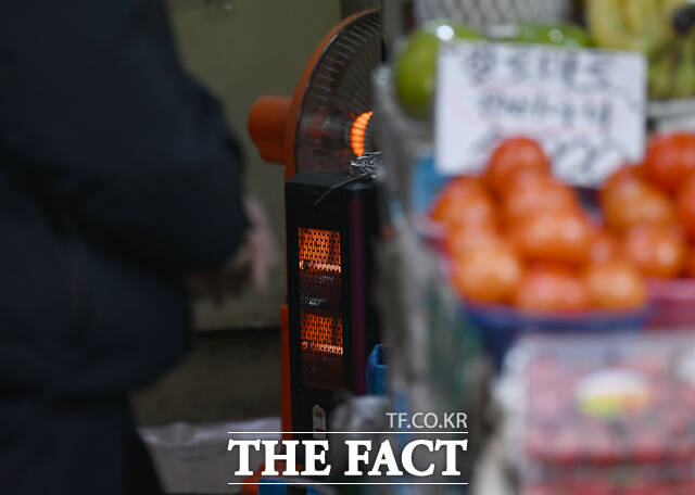 한 상인이 난로를 쬐며 가게를 지키고 있다.