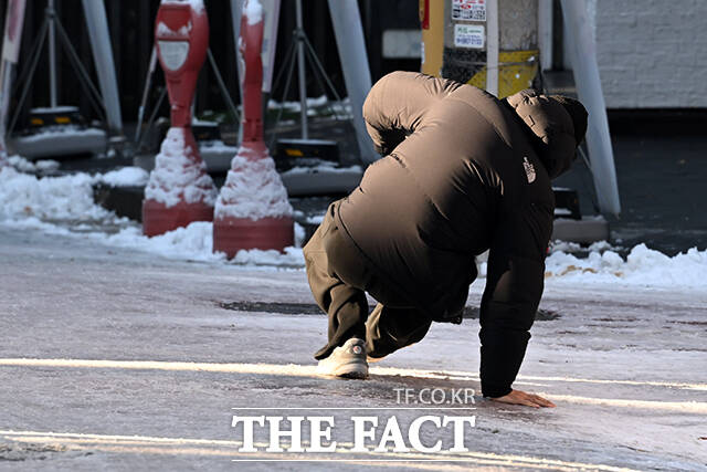 한 시민이 빙판길을 걷다가 넘어지고 있다.