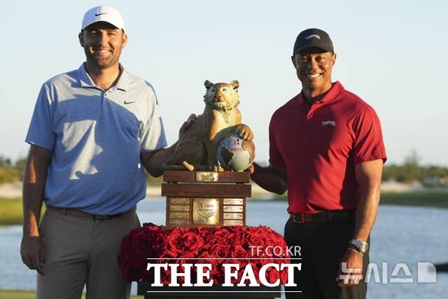 셰플러(왼쪽)가 2024년 히어로 월드챌린지에서 우승한 뒤 호스트인 타이거 우즈와 우승컵을 가운데 두고 포즈를 취하고 있다./AP.뉴시스