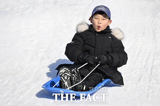 눈썰매를 타고 있는 어린이.