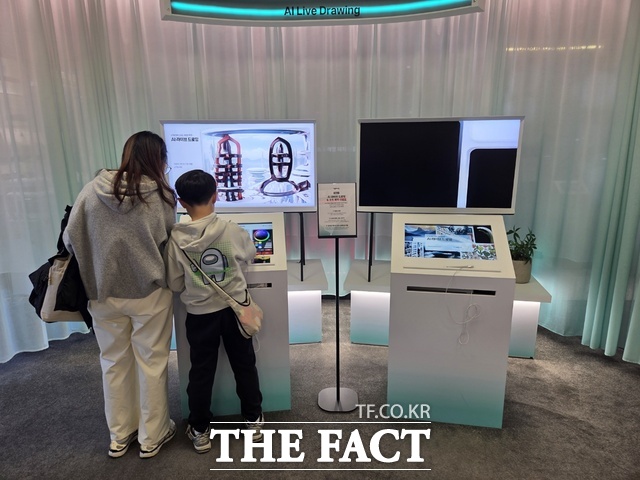지난 22일 서울 광화문 KT사옥 KT 온마루 전시관을 찾은 한 모자 방문객이 대한민국 통신 역사를 체험한 뒤 전시관 내에 설치된 AI 라이브 드로잉을 체험하고 있다. /종로=우지수 기자