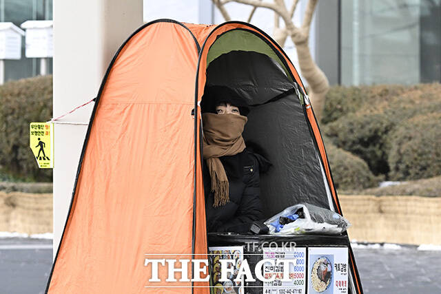 목요일인 29일 중부지방과 경북권 중심으로 한파특보가 발효되는 등 강추위가 이어지겠다. 전국이 대체로 맑겠으나 충남권, 전라권, 제주도에는 가끔 구름이 많겠다. 사진은 한파가 이어진 지난 26일 오전 서울 영등포구 여의도환승센터 인근에서 한 상인이 추위를 피하고 있는 모습/ 송호영 기자