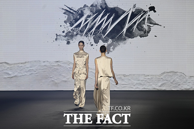 두 모델이 런웨이를 걷고 있다.