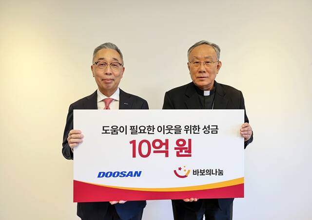박지원 두산그룹 부회장(왼쪽)이 지난 3일 서울 명동성당에서 열린 성금 전달식에서 바보의 나눔 이사장 구요비 주교와 함께 기념 촬영을 하고 있다. /두산그룹