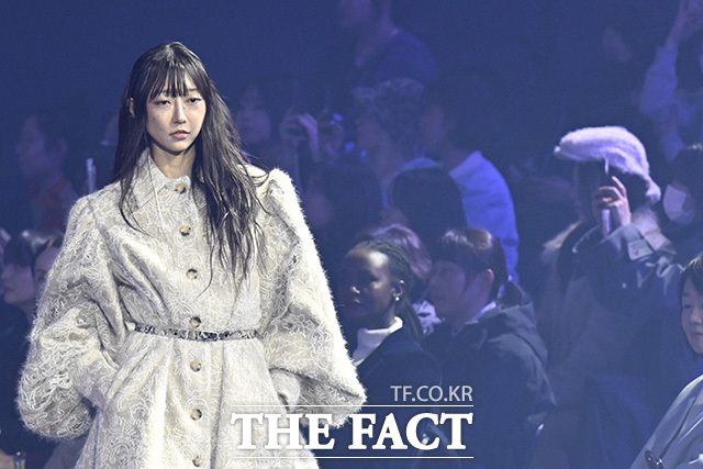 관객들이 한 모델의 캣워크를 관람하고 있다.