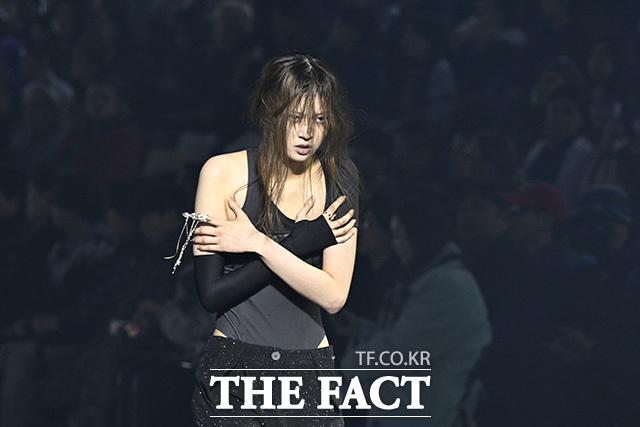 한 모델이 런웨이를 걷고 있다.