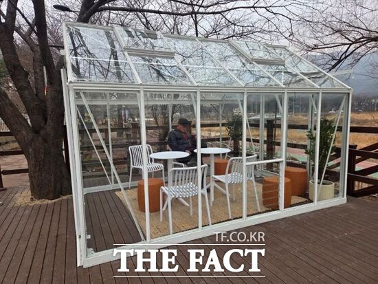 의정부시가 한파 대비 방풍시설로 호원천에 설치한 유리온실 형태의 따숨터에서 한 시민이 휴식을 취하고 있다. /의정부시