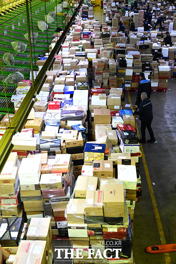 이른 새벽부터 시작된 택배 분류 작업에서 작업자들이 외투를 벗은 채 업무에 집중하고 있다.