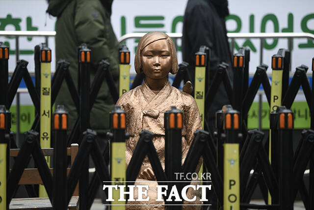 평화의 소녀상 뒤로 시민들이 지나가고 있다.