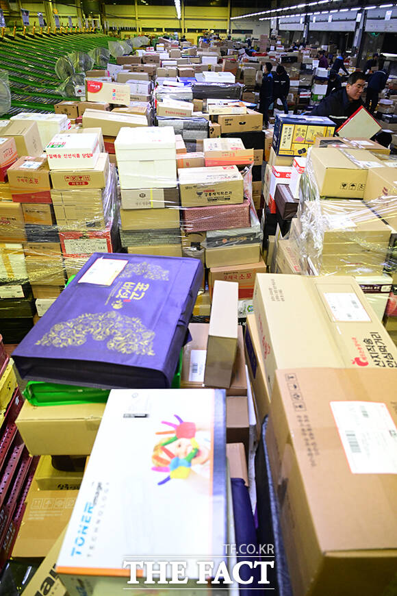 이른 새벽부터 시작된 택배 분류 작업에서 작업자들이 외투를 벗은 채 업무에 집중하고 있다.