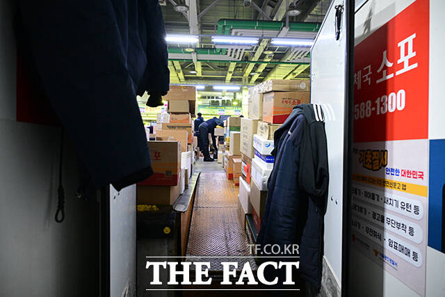 이른 새벽부터 시작된 택배 분류 작업에서 작업자들이 외투를 벗은 채 업무에 집중하고 있다.