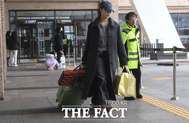 한 승객이 양손 가득 짐과 함께 버스에 탑승하기 위해 이동하고 있다.