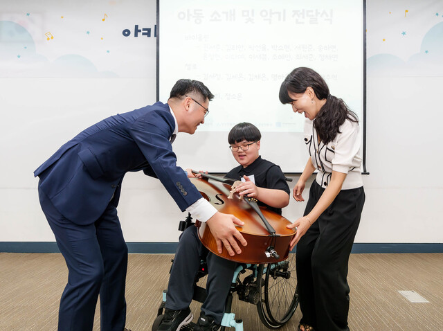 유준원 상상인그룹 대표(왼쪽)가 휠체어 사용 아동에게 오케스트라 악기를 수여하고 있다. /상상인그룹