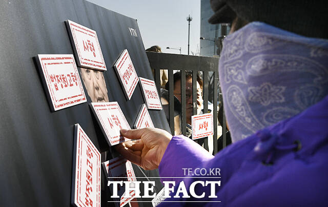 내란수괴 윤석열 엄중 처벌 촉구 기자회견이 19일 오전 서울 종로구 광화문 월대 앞에서 열린 가운데 한 참가자가 윤석열 사진에 법정 최고형 도장을 부착하고 있다. /박상민 인턴기자