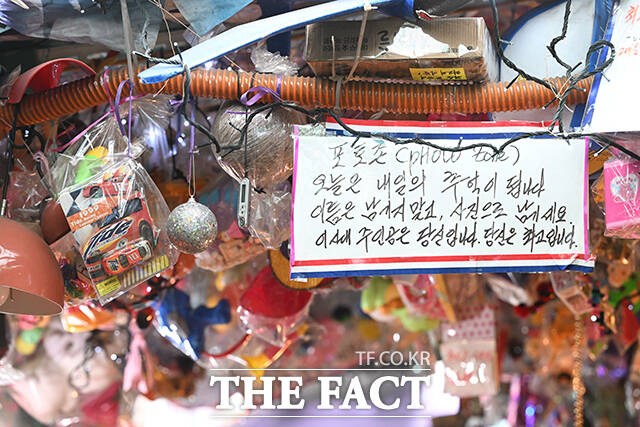 정 씨의 매장에 걸려있는 팻말. 오늘은 내일의 추억이 됩니다. 이름은 남기지말고, 사진으로 남기세요. 이 시대 주인공은 당신입니다. 당신은 최고입니다라고 적혀있다.