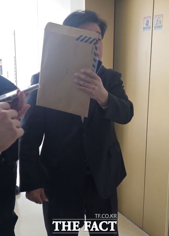 모욕 혐의로 재판에 넘겨진 양우식 경기도의원이 12일 첫 공판을 마치고 재판정을 나서면서 얼굴을 가린 채 취재진의 질문에 답하고 있다. /이승호 기자